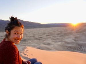 IWRC staff member Aya in a red sweater sitting on a dune in sunllight