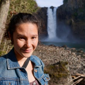 Staff member Aya Cockram standing in front of a waterfall.